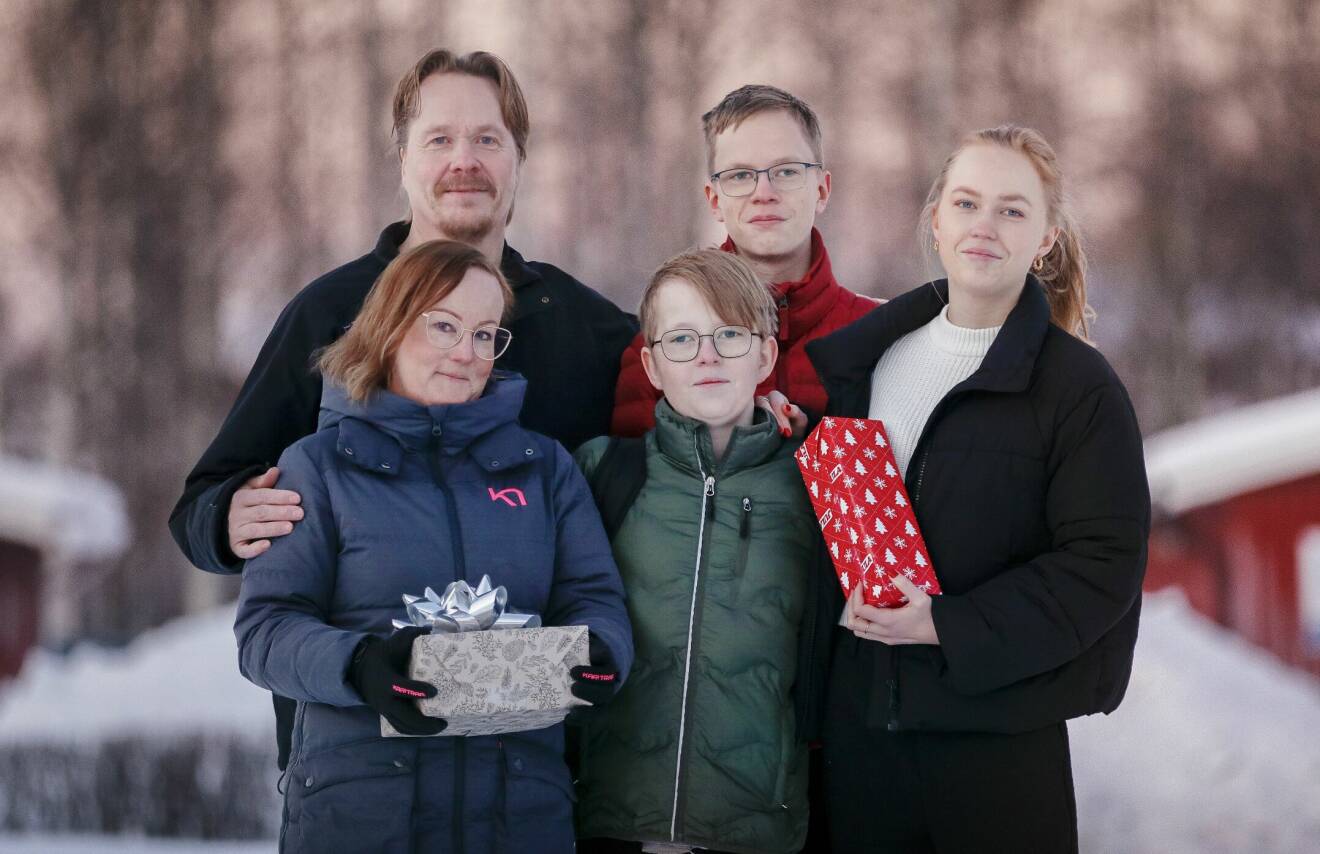 Porträttbild på mamma Carola och pappa Lars och deras två söner och dotter. De står utomhus med vinterjackor på sig. Carola och dottern håller i varsin julklapp.