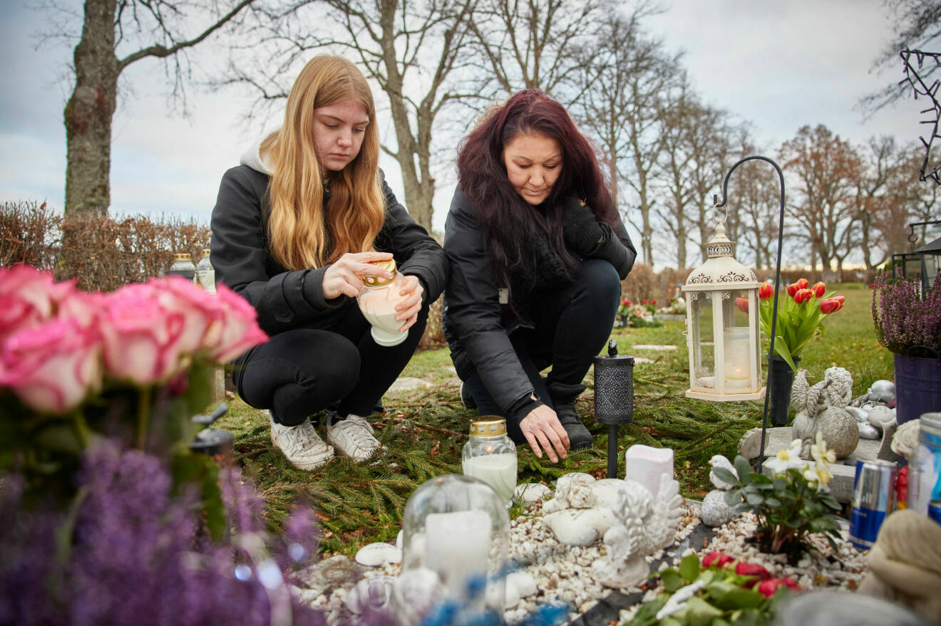 Jennifer och Michaela sitter hukade på en kyrkogård vid Dennis grav som har massa blommor och gravljus vid sig.
