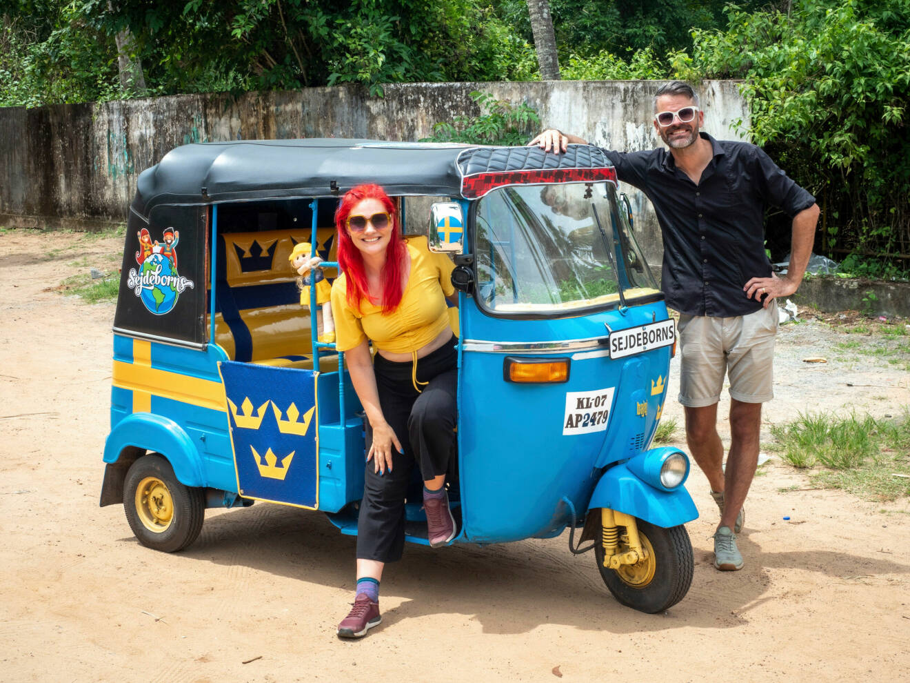 Louise och Anders står vid sin svenskmålade tuk-tuk i Indien.