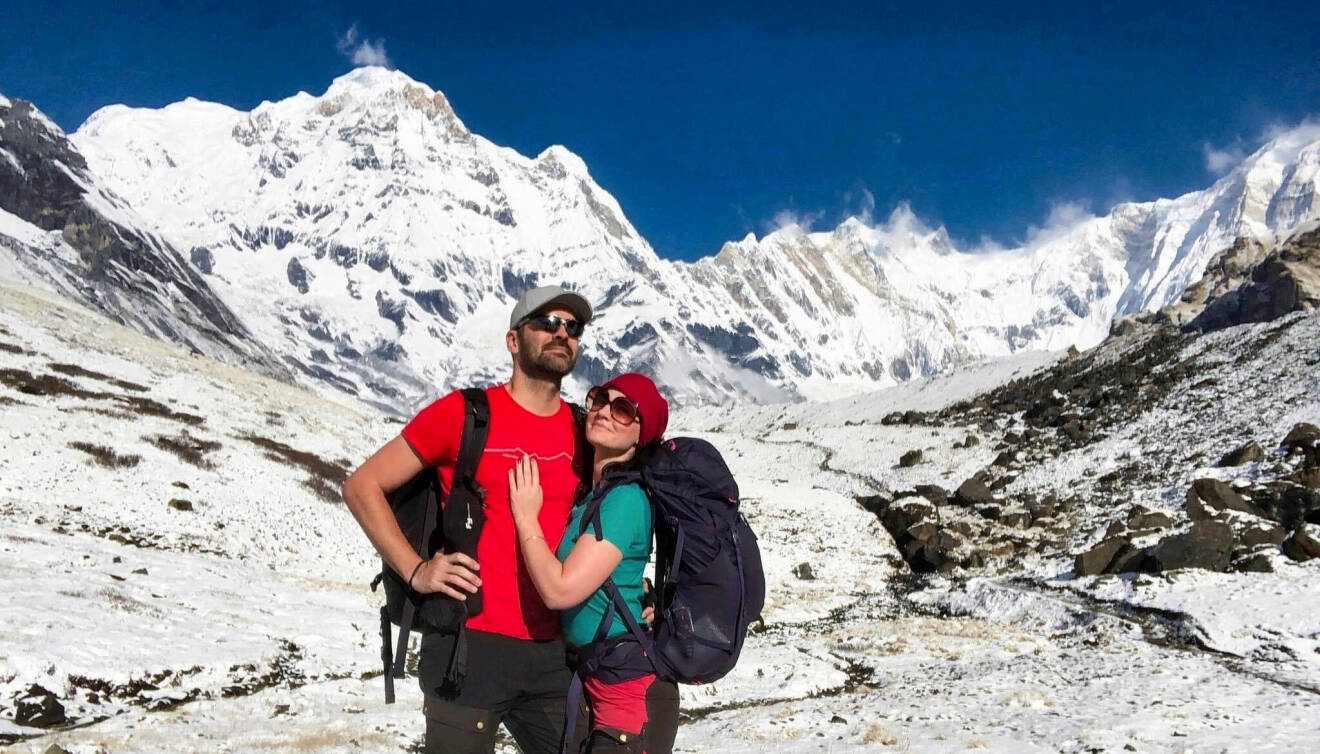 Anders och Lousie Sejdeborn står på en snötäckt bergstopp. De har friluftskläder med ryggsäck på sig.