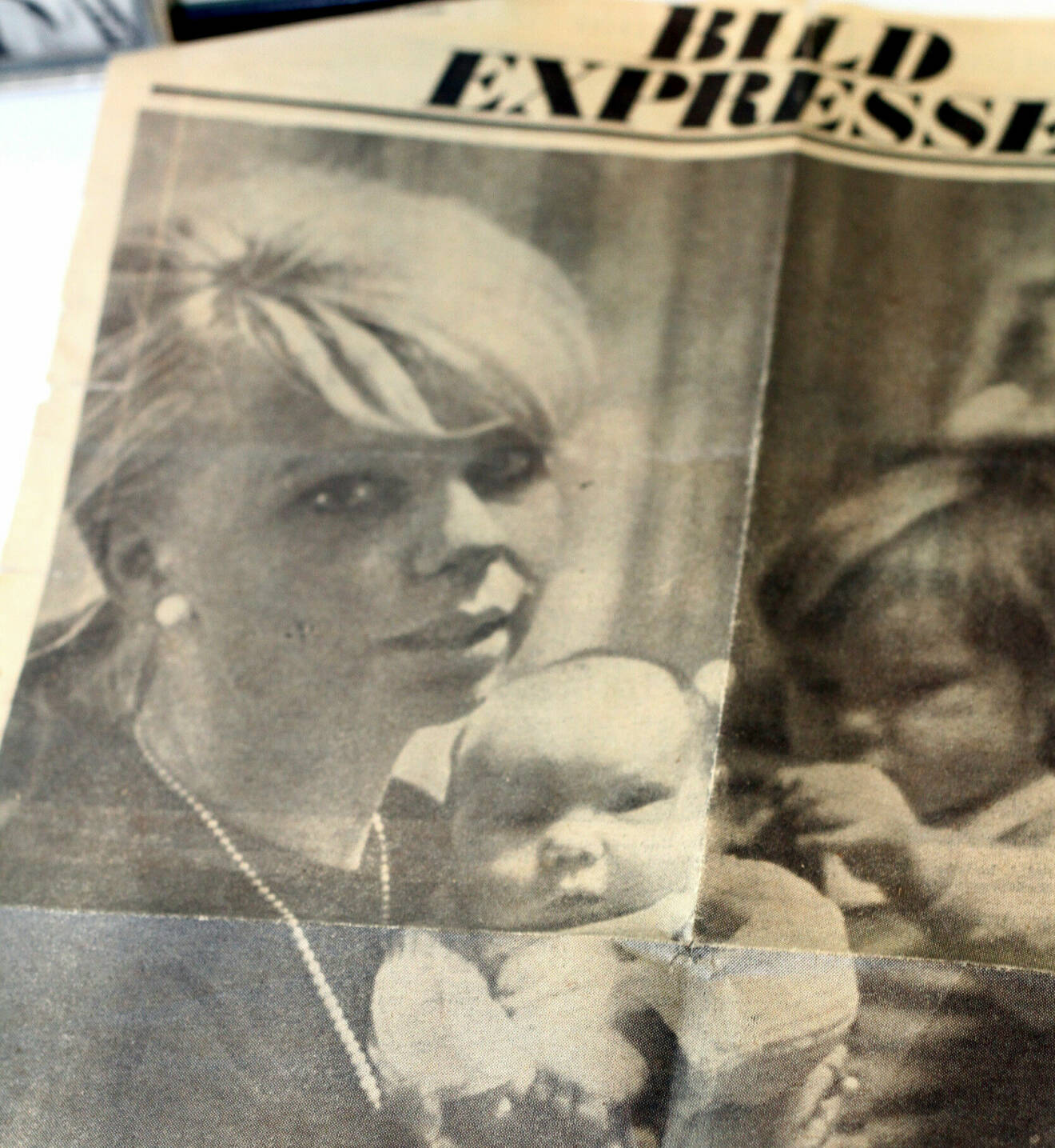 Gammalt tidningutklipp från Expressen på en kvinna med en bebis och en liten flicka i famnen.