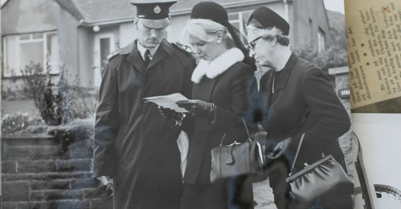 En man och två kvinnor med svarta sorgekläder vid en begravning.