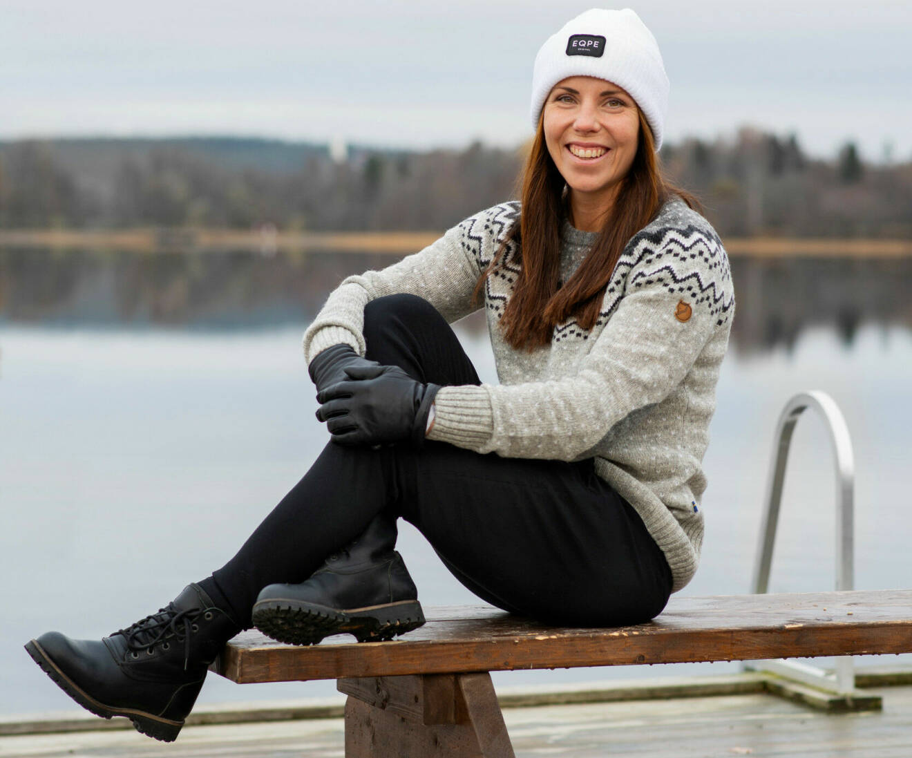 Charlotte Kalla sitter på en bänk framför en sjö.