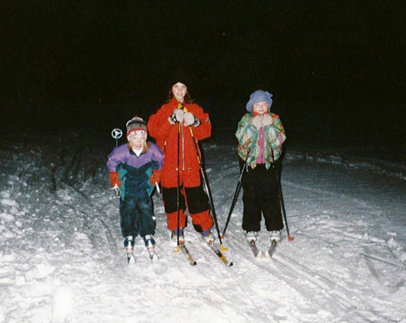 Charlotte Kalla som barn tillsammans med sina systrar Christelle och Cecilia. De åker skidor och det är mörkt ute.