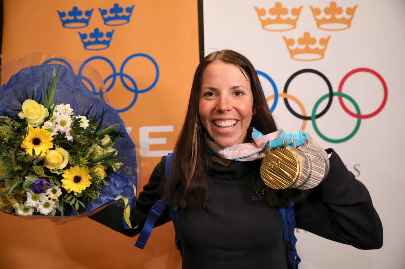 Charlotte Kalla under vinter-OS i Sydkorea 2018. Hon håller upp en blombukett och en guld- och tre silvermedaljer.