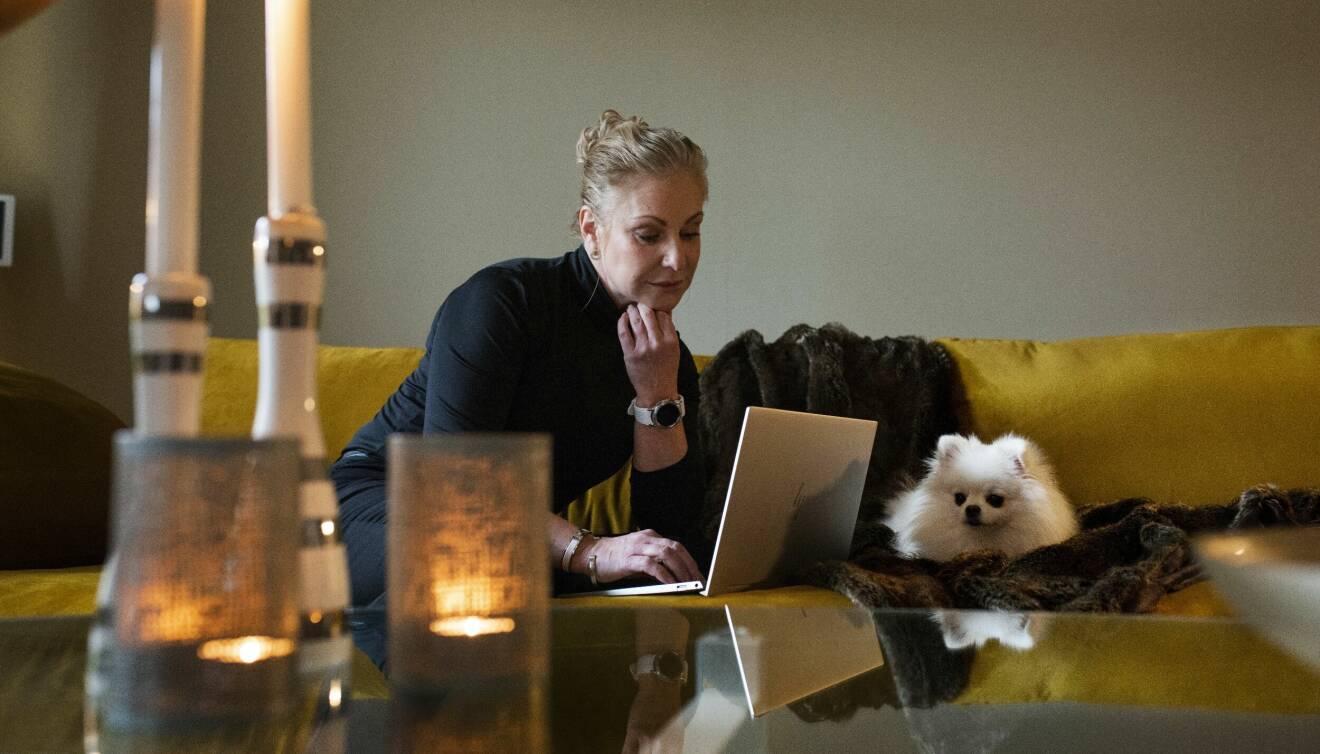 Åza Brennander sitter i sin soffa med sin dator och hund.