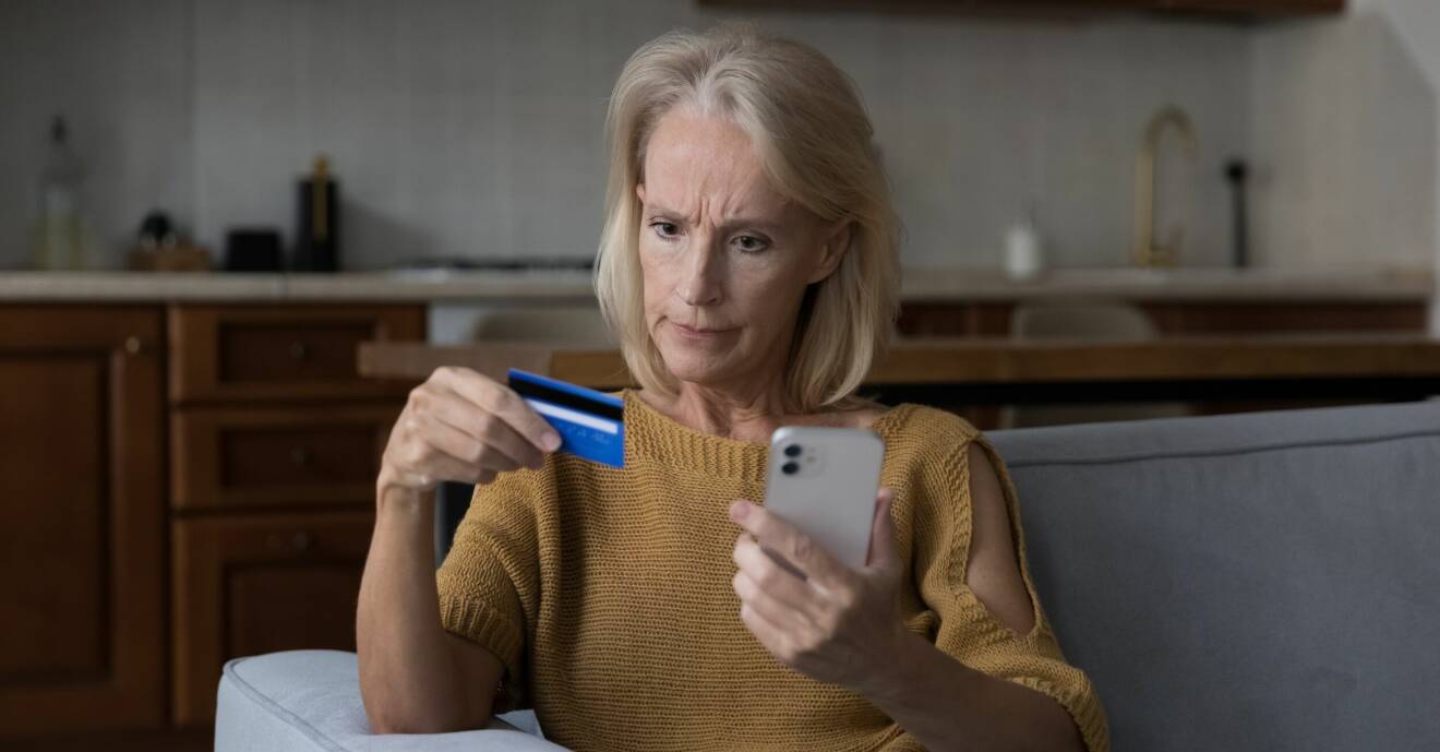 Kvinna håller i en mobiltelefon och ett bankkort.