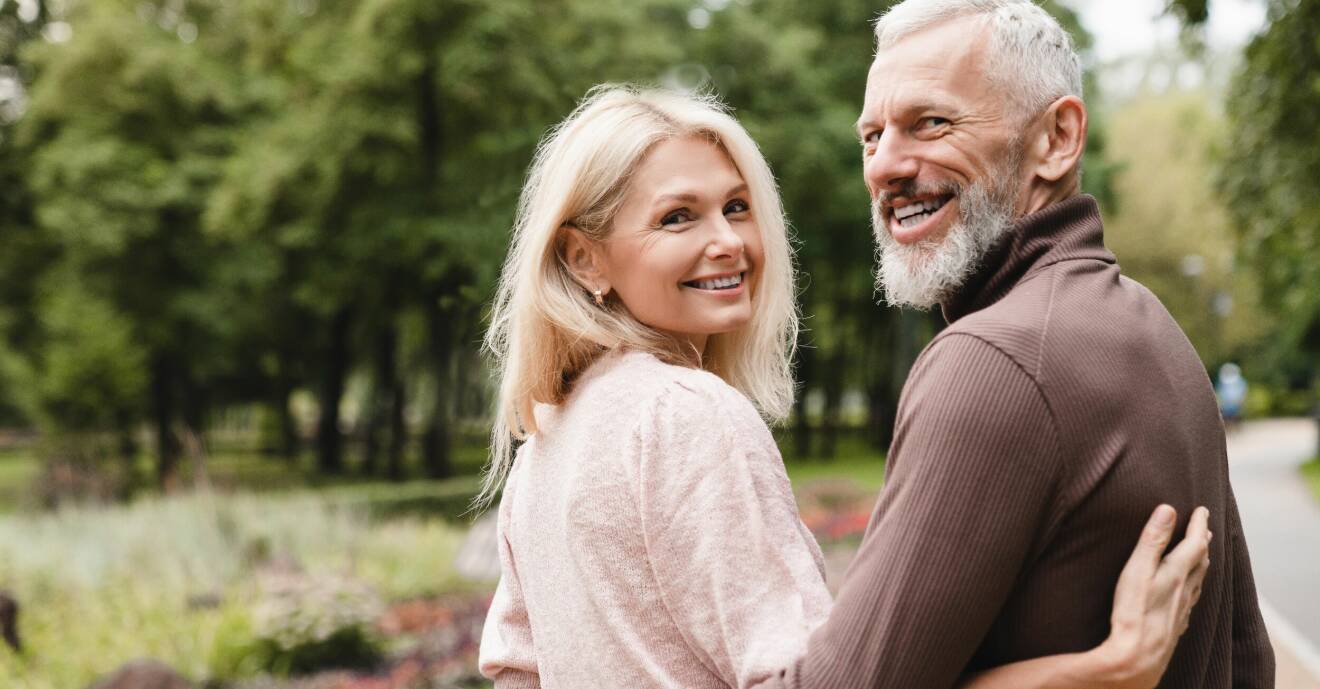 En kvinna och en man står utomhus och håller om varandra och ler.