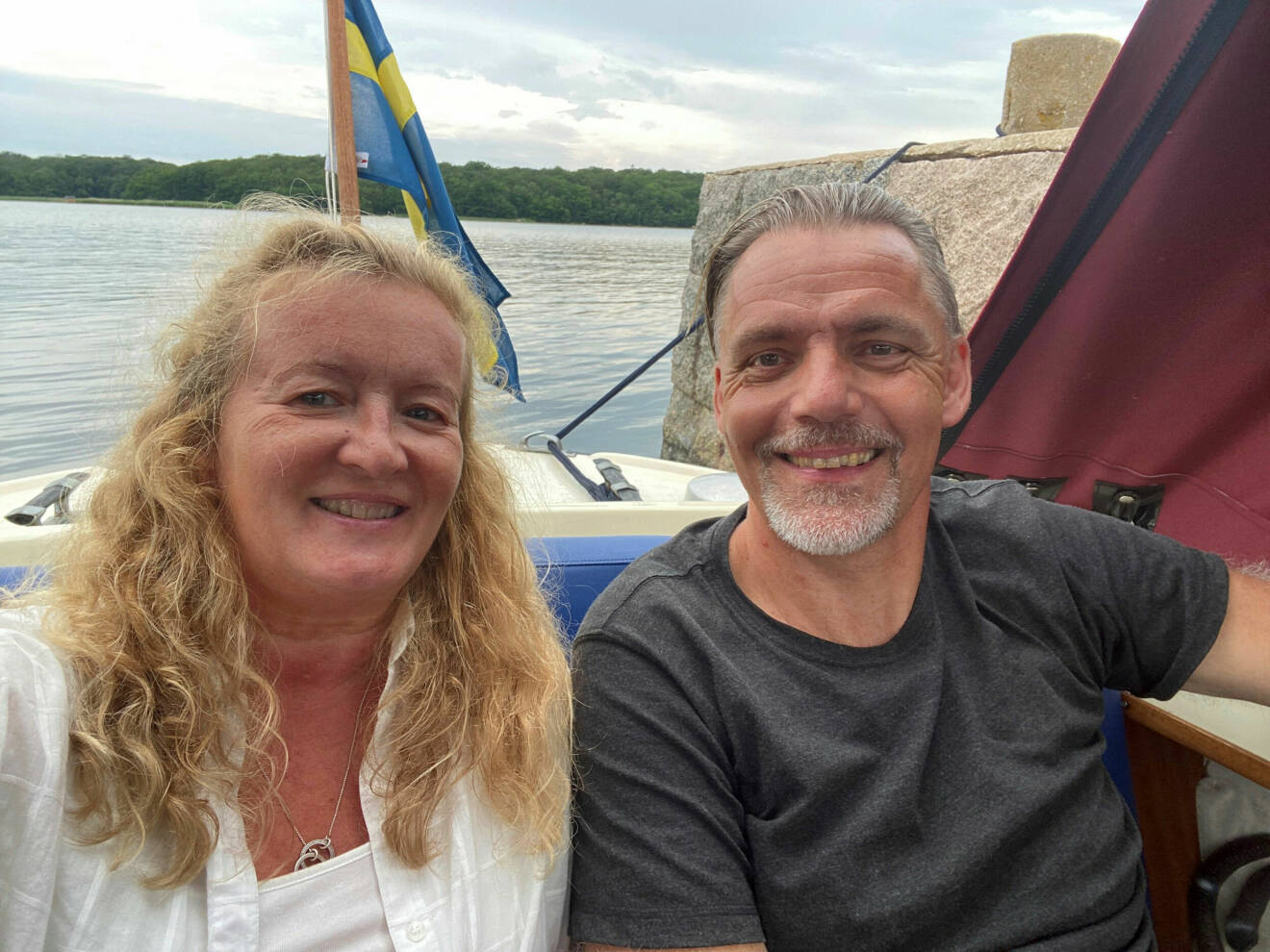 Helene och Tomas sitter i sin båt, i bakgrunden syns vatten.