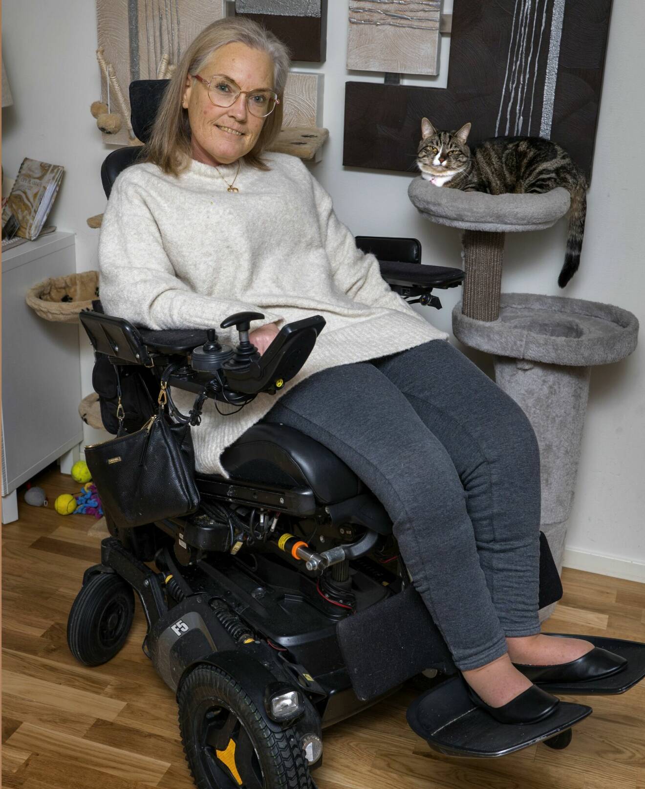 Anna sitter i sin rullstol och hennes katt sitter brevid.