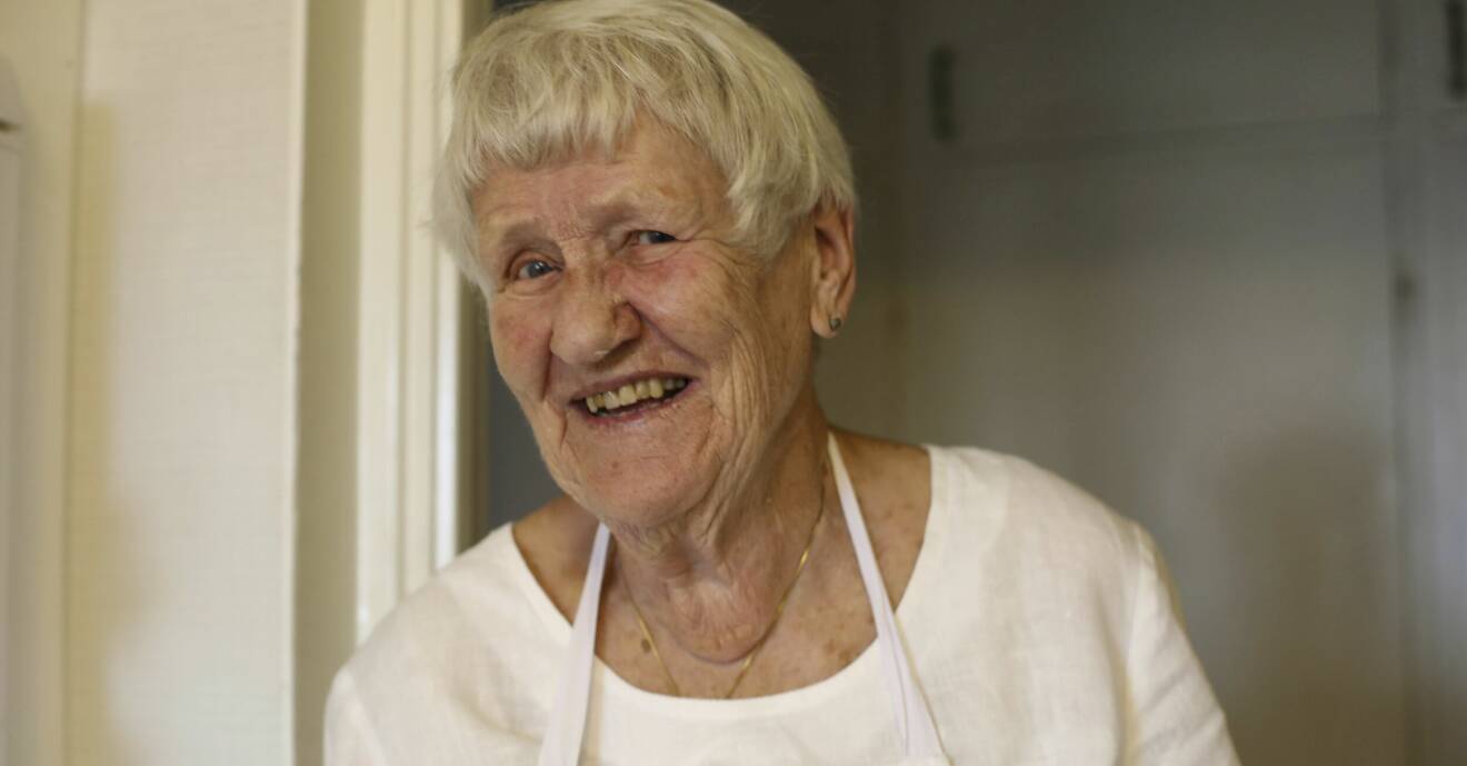 90-åriga Carin, hon har kort grått hår och vit tröja.