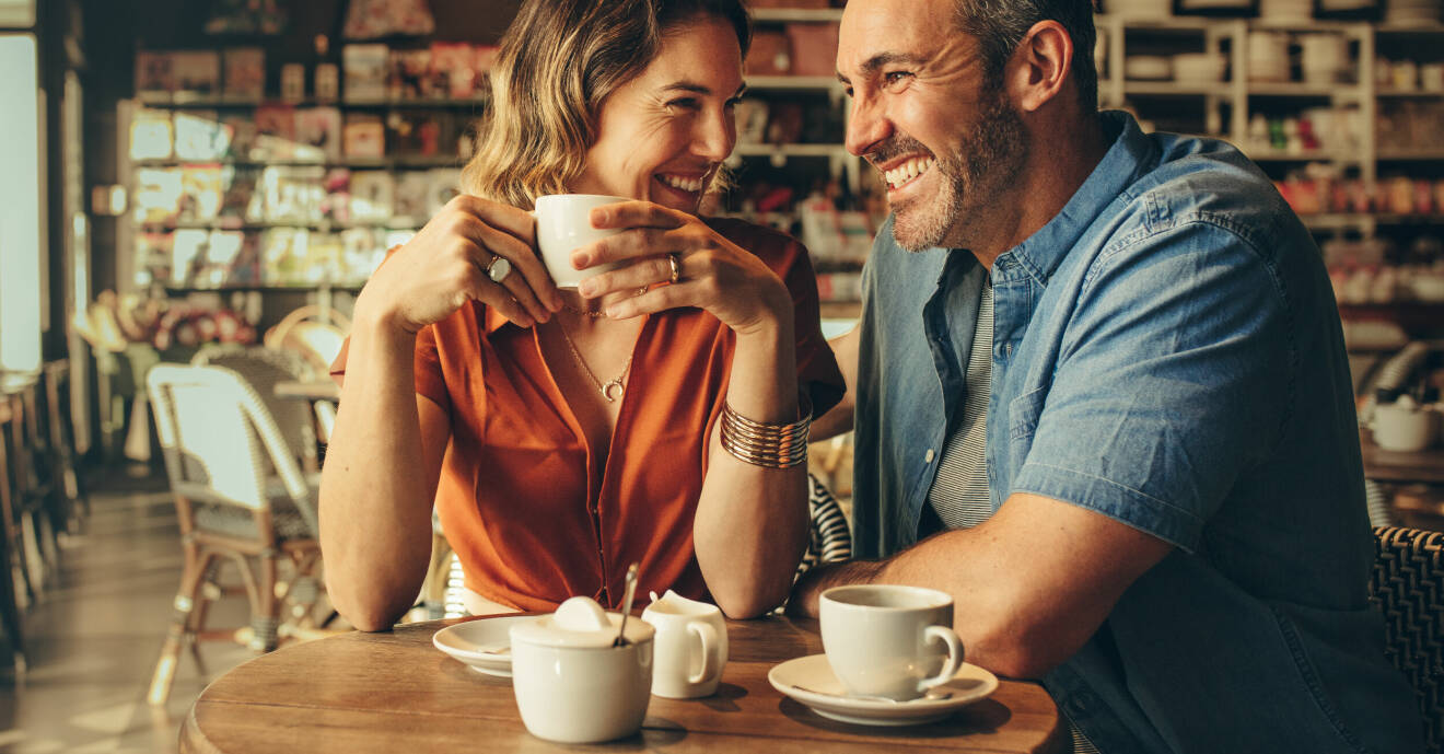 En man och en kvinna sitter på ett café och fikar. De skrattar.