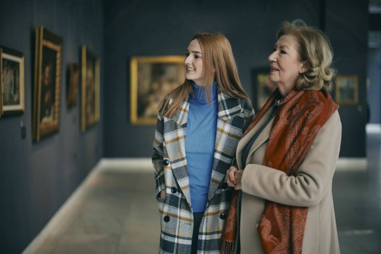 Två personer på ett museum som tittar på tavlor.