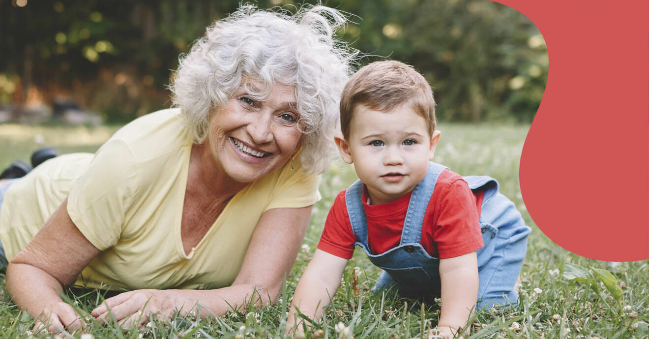 En mormor eller farmor som leker i gräset med sitt barnbarn.