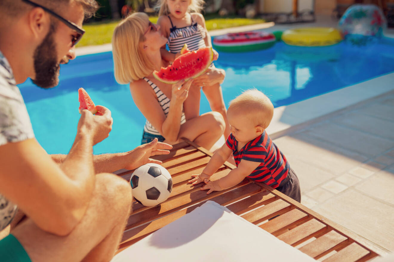 En barnfamilj som sitter vid en pool.