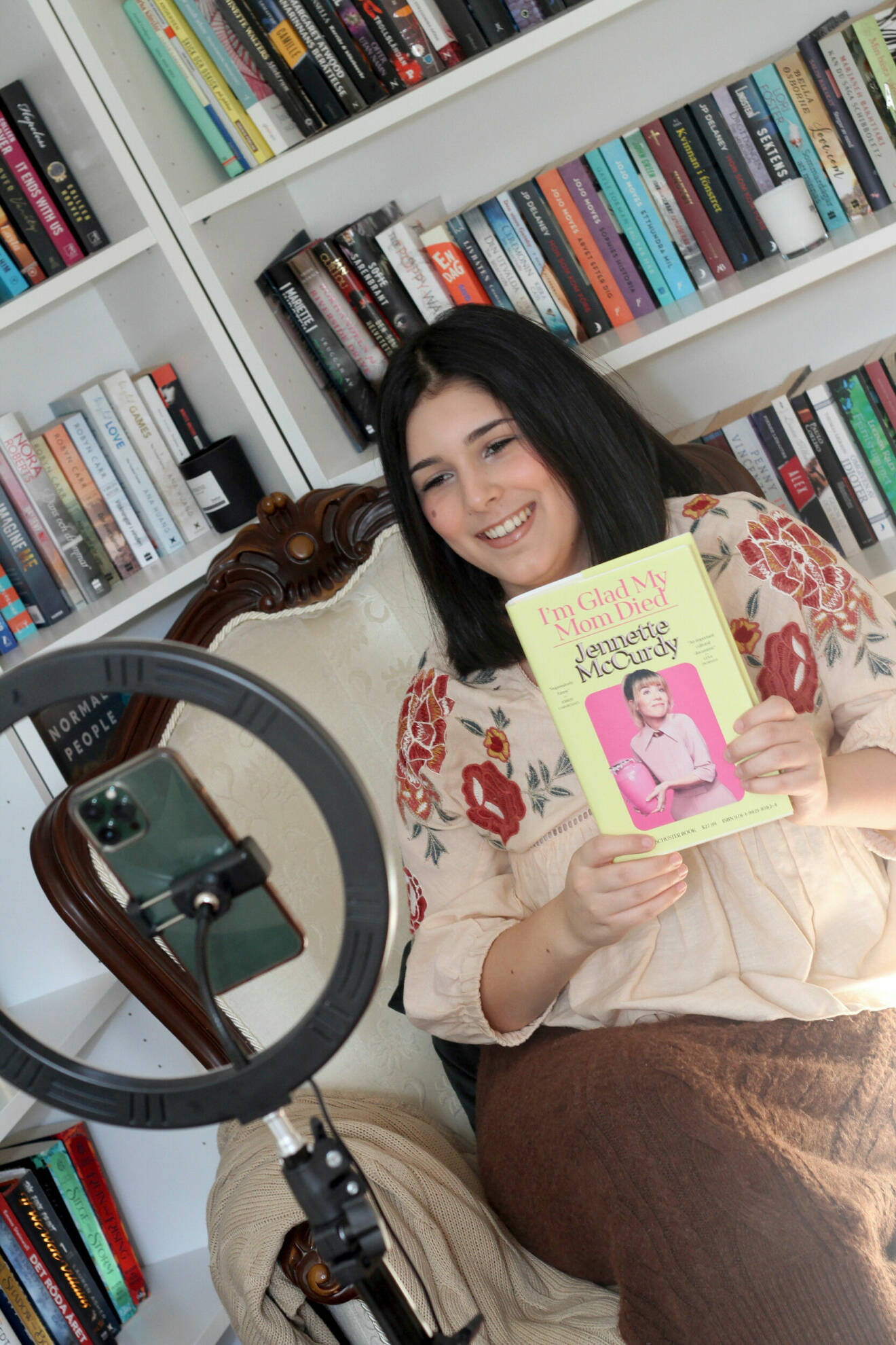 Foto på Jasmine som håller upp en bok framför mobilen och ringlampan.