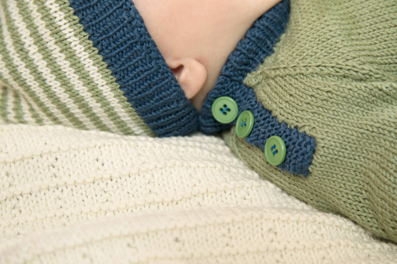 Knäppning med knappar på en stickad babytröja.