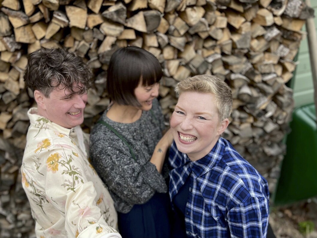 Odd, Helena och Mariette står framför timmerstockar och håller om varandra och ser glada ut.