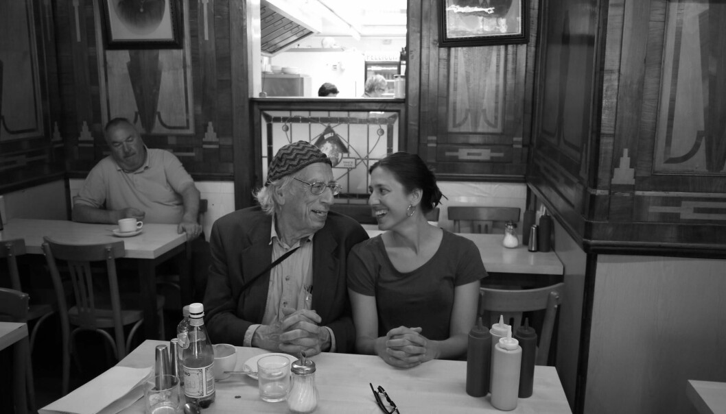 Izzy Young och hans dotter Philomène Grandin sitter på en restaurang och ler stort mot varandra
