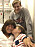 En kvinna i medelåldern ligger i en sjukhussäng omgiven av sina två tonårssöner.