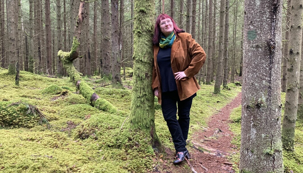 I debutromanen och två kommande böcker djupdyker Ingela Wadbring i tvåsamhetsnormen och i hur vi människor ser på relationer. Ingela Wadbring, professor och författare, står lutad mot ett träd i skogen.