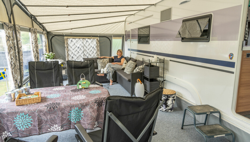 Inger Axelsson sitter i en soffa som är placerad i förtältet till hennes husvagn.