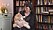 Irene Svensson håller en av sina katter och står framför en välfylld bokhylla.