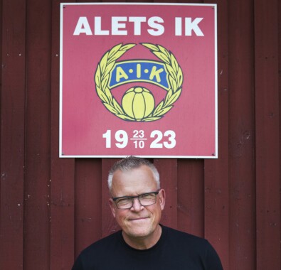 Janne besöker ofta moderklubben, Alets IK där allt började. Janne porträtt under röd Alet-skylt.