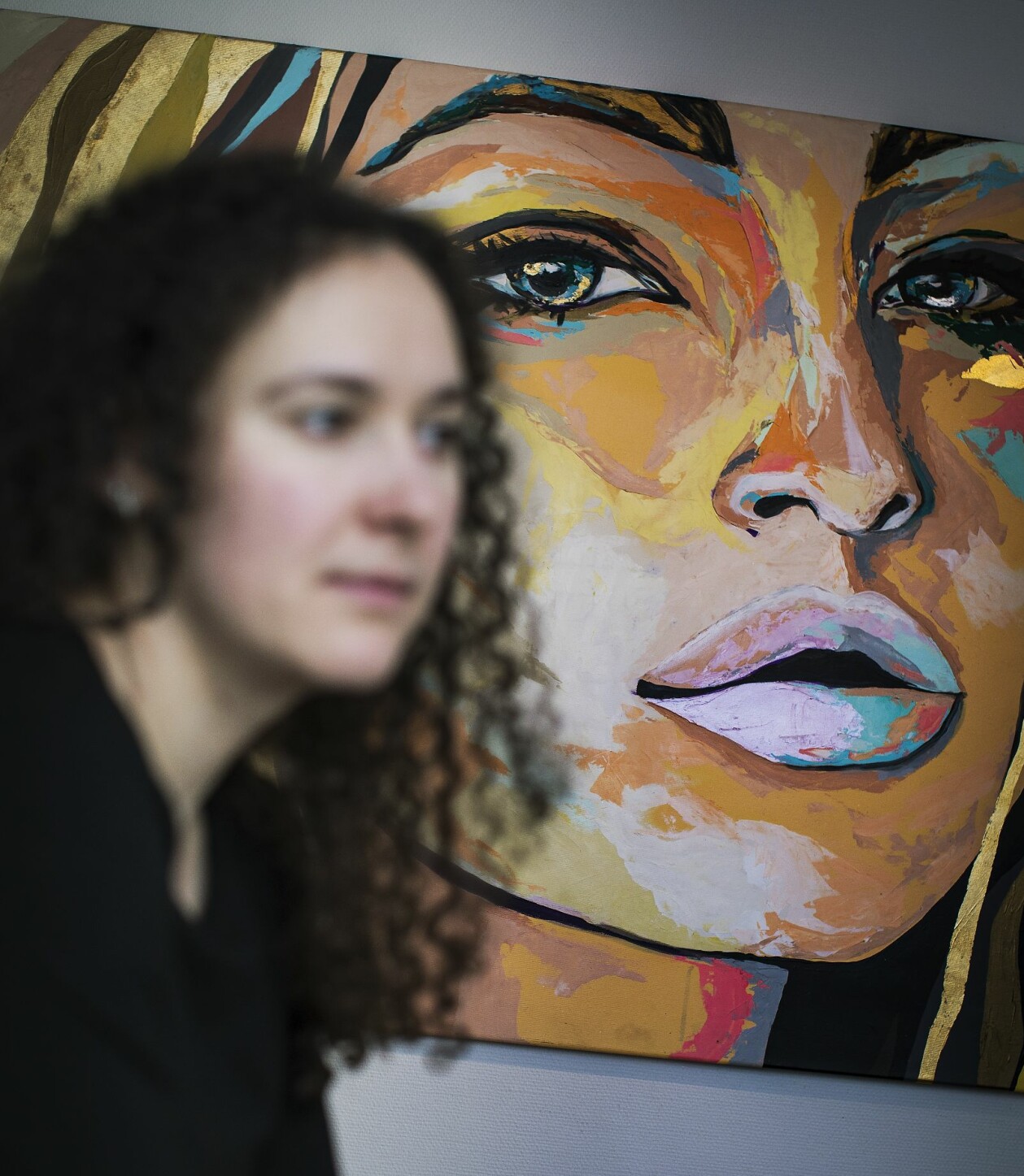 Jasmina tvingas pausa intervjun och torka tårarna flera gånger. Foto: Veronika Kindblad "Jasmina" som är suddig i framgrunden sitter framför en tavla på Talitas kontor i Stockholm.