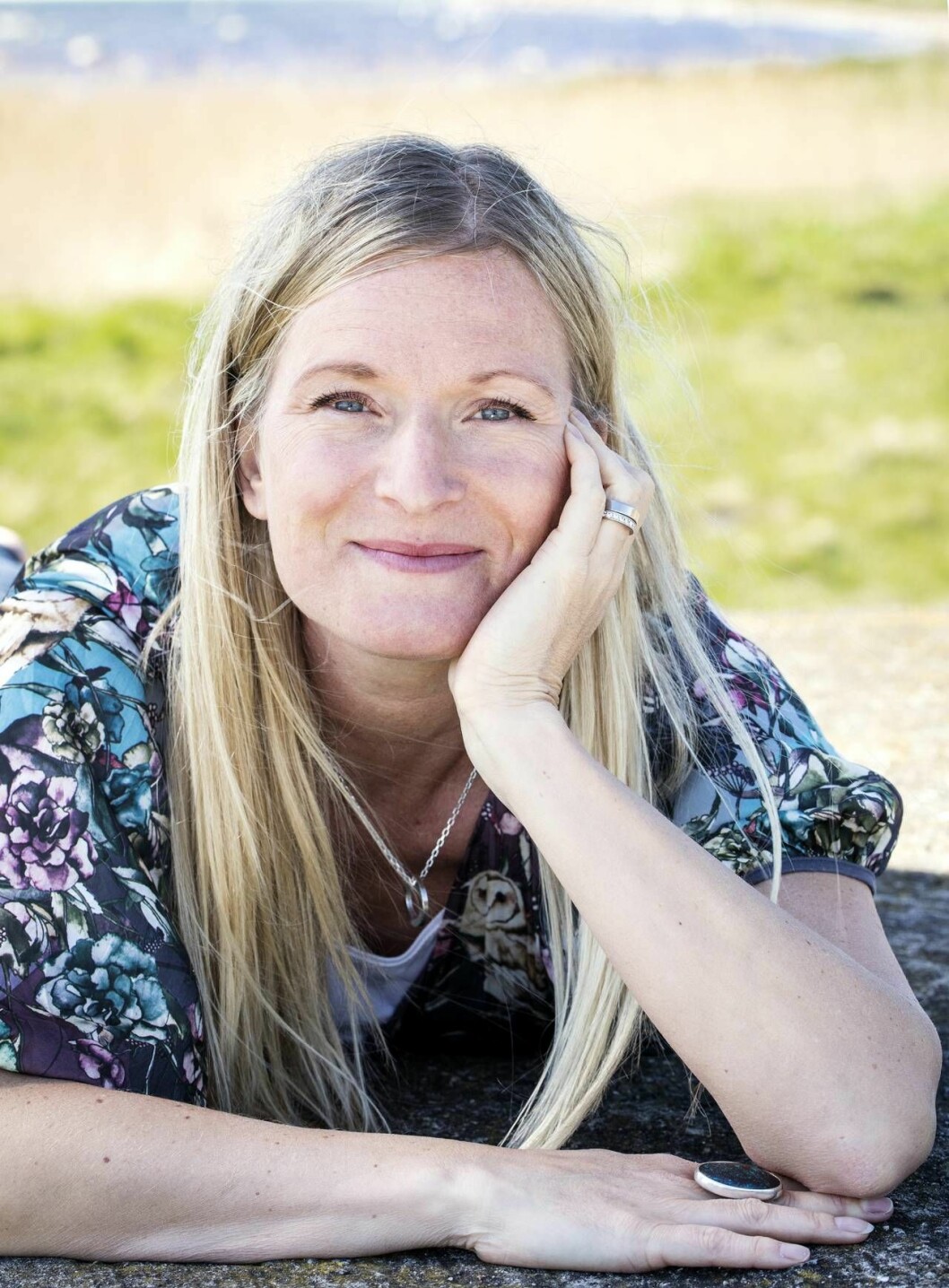 Jenny Åsenlund med hakan i handen och vacker natur i bakgrunden