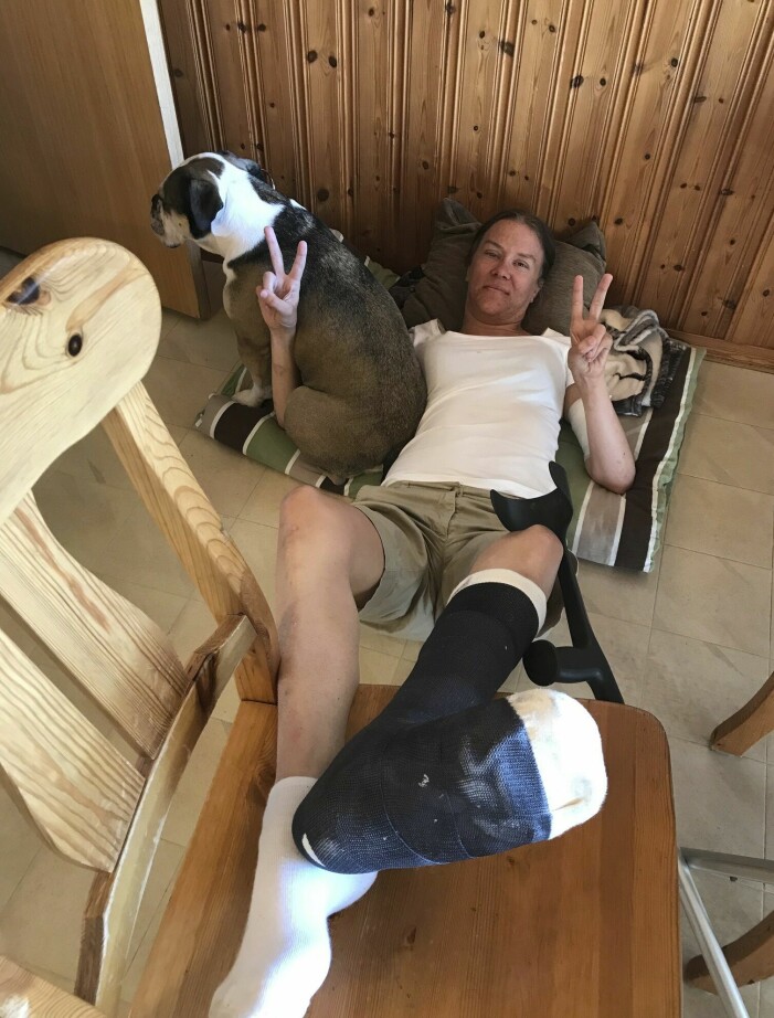 Transplantationen fick vänta då först ett svårläkt benbrott kom emellan och sedan ett svårläkt sår under ena foten. Jessica ligger på golvet och gör v-tecken. Hon har fotleden i gips, och hunden Elsa sitter bredvid.