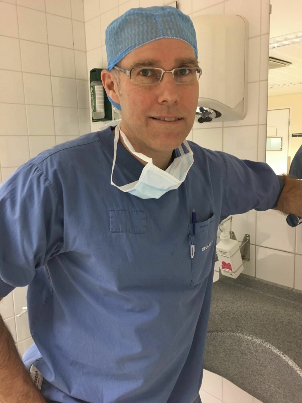 Manlig läkare med glasögon i blå op-klädsel