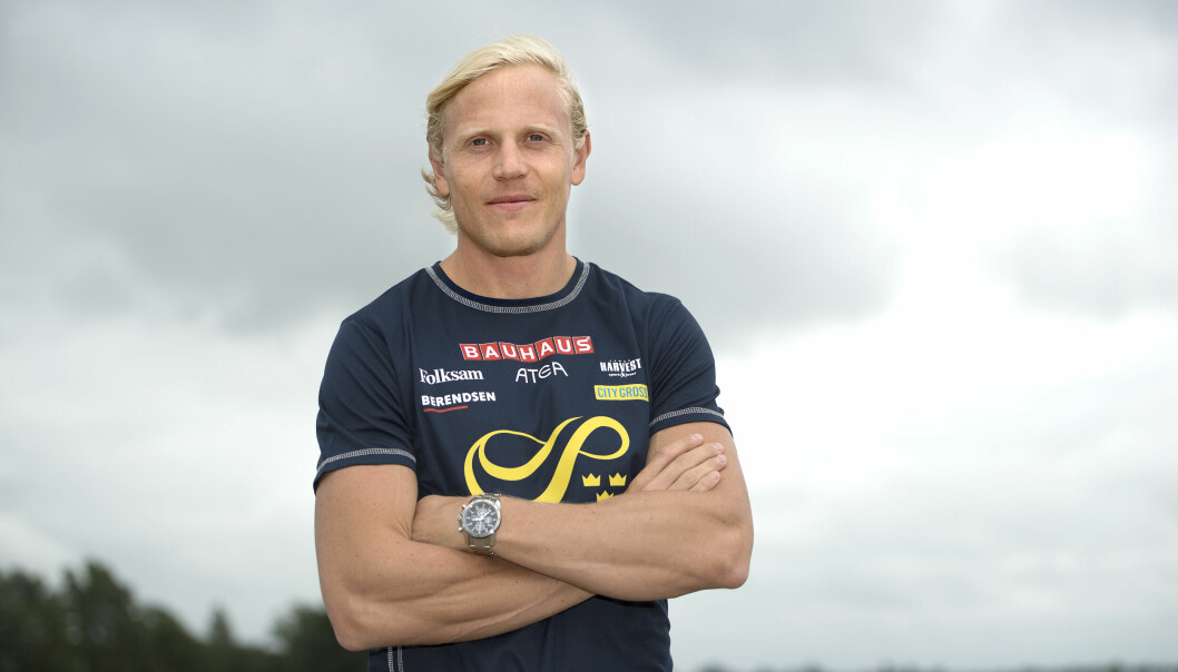 Friidrottaren Johan Wissman står med armarna i kors och tittar in i kameran. I bakgrunden en mulen himmel.