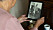 Jopie syns suddigt i förgrunden och håller upp ett gammalt svartvitt fotografi på sin pappa i handen.