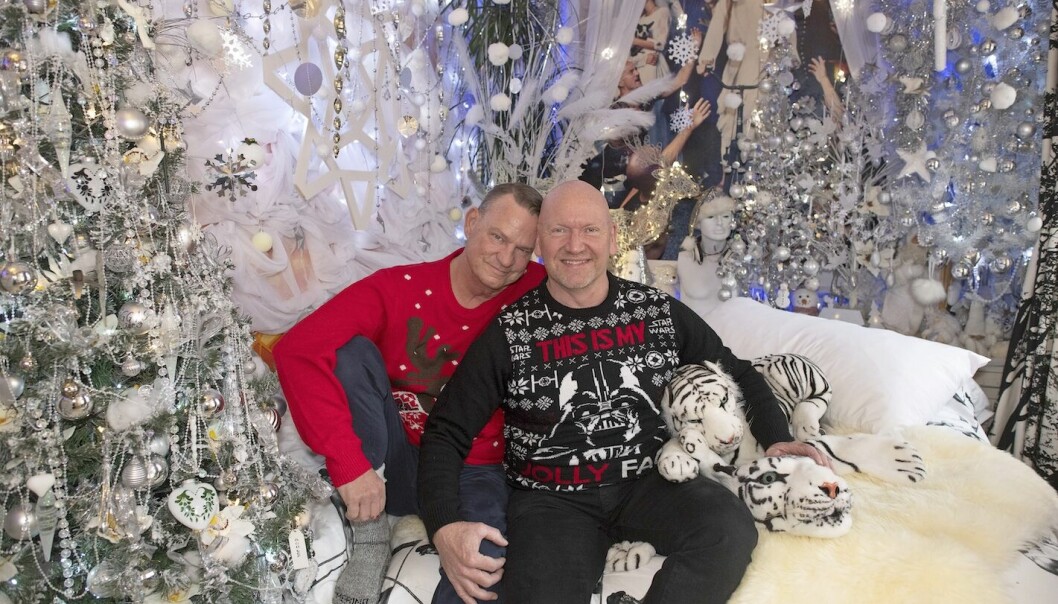 Pehr och Richard i sina jultröjor sitter på sängen. sovrummet som är pyntat i vitt och silver.