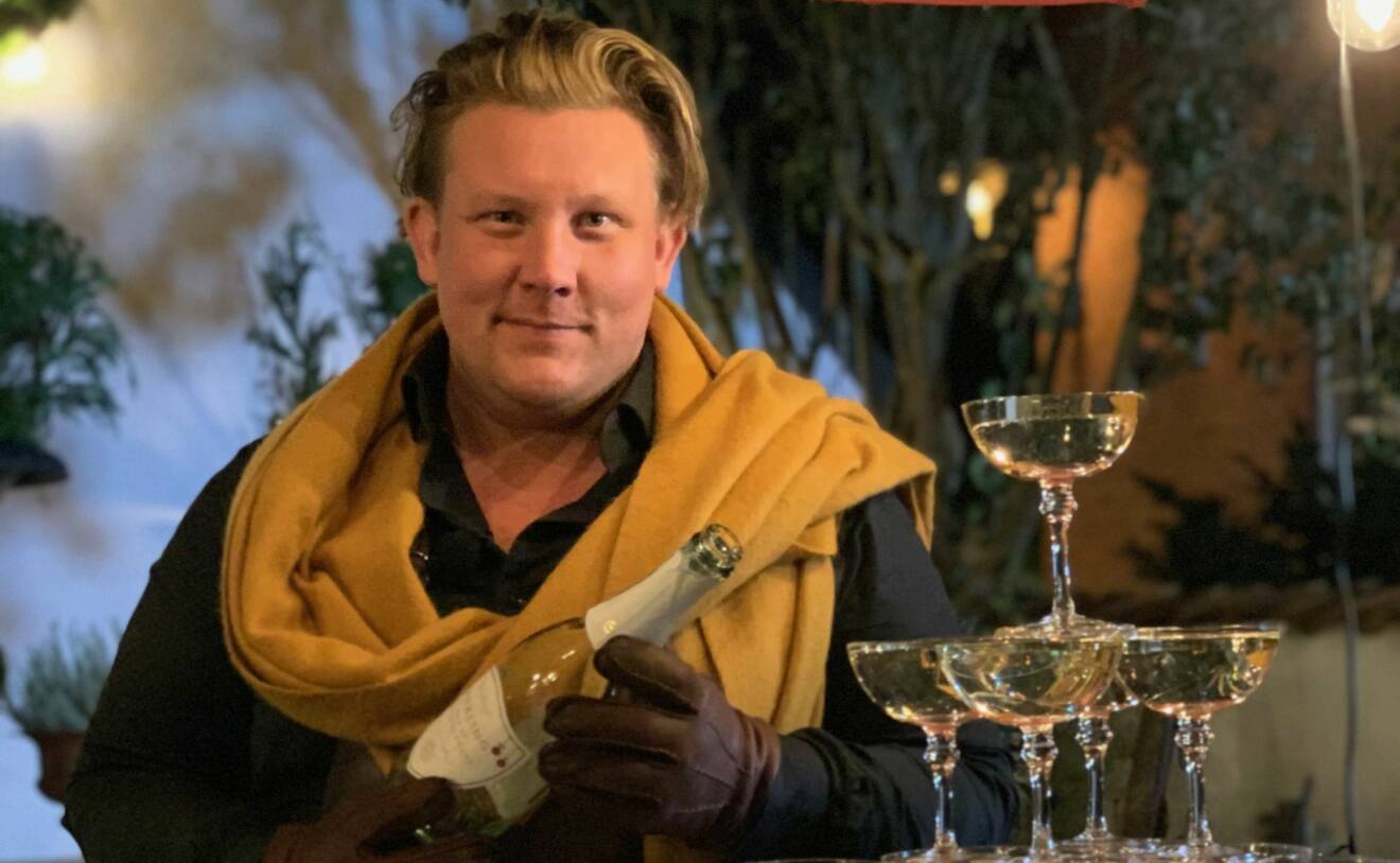 Karl Fredrik Gustafsson häller upp champagne i glas ställda i pyramid.