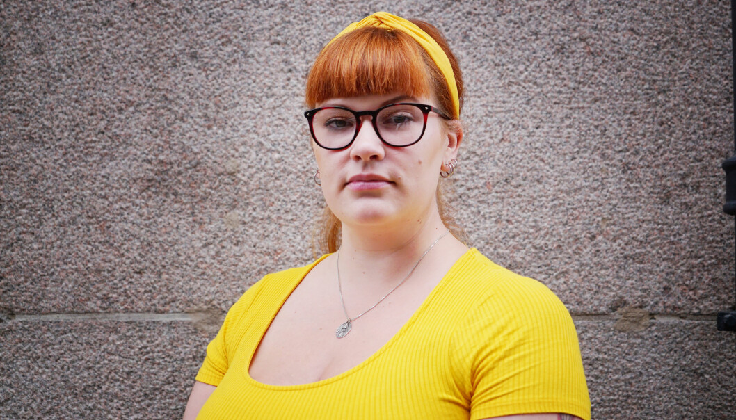 Katarina Svensson Flood i en gul outfit framför en stenvägg.