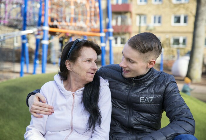 En ung man håller om sin mamma, de båda ler och ser på varandra.