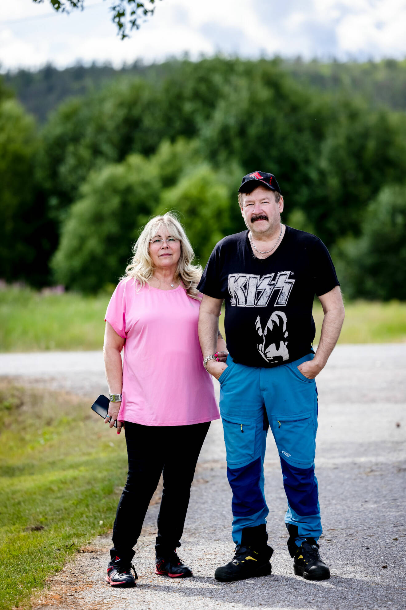Anette och hennes sambo Kjell står och tittar in i kameran. Hon bär en rosa t-shirt och han en svart med rockbandet Kiss på.