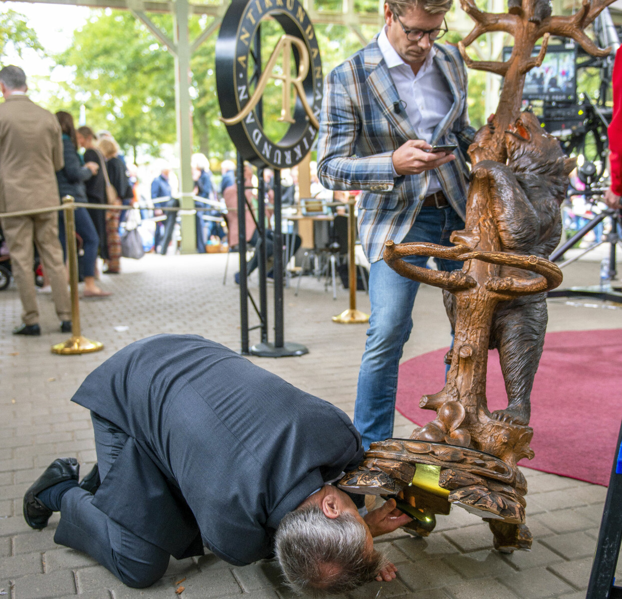 ”Det borde finnas en signatur eller ett par initialer!” Knut Knutson är inte den som drar sig för grundliga undersökningar. Rickard Thunér agerar stöttepelare samtidigt som han försöker leta uppgifter på nätet om den ovanliga klädhängaren med inbyggt käppställ. Foto: Erik Karlsson Knut Knutson letar efter en signatur under en stor klädhängare.