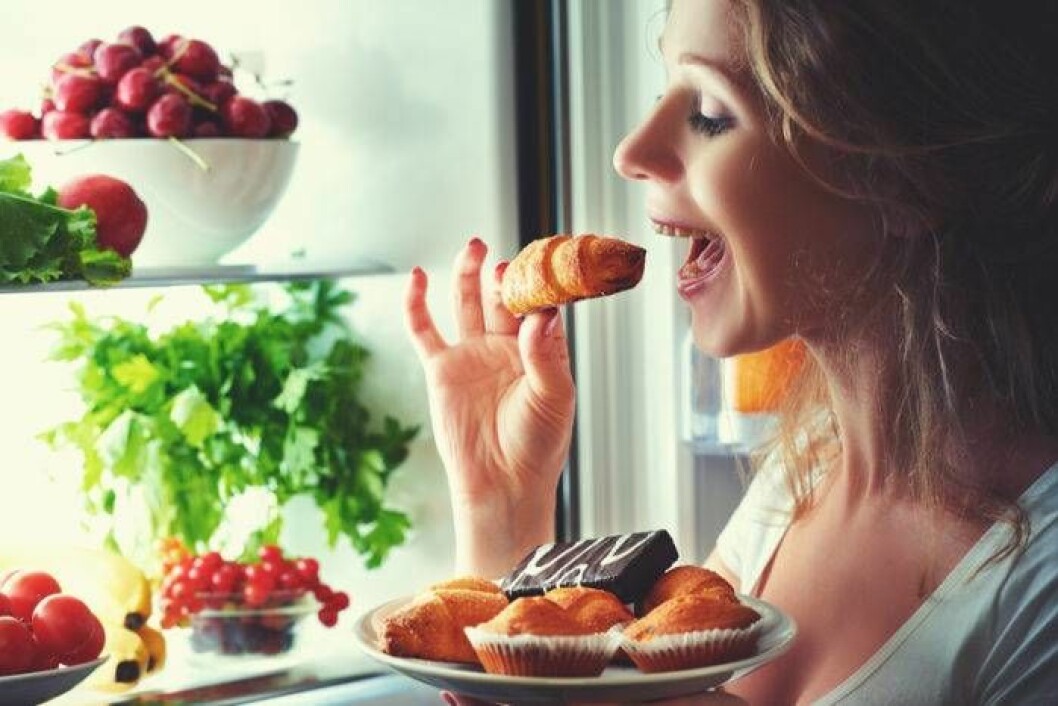 Faller du för frestelsen på kvällen? Foto: Shutterstock/IBL Kvinna äter sötsaker från kylen