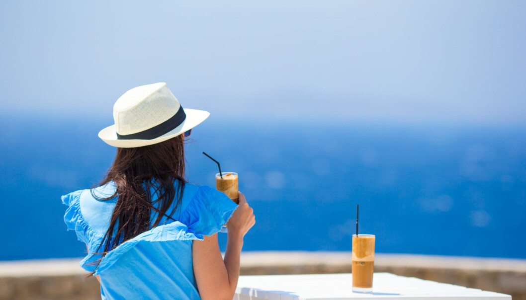 Att ta en solsemester kan vara ett bra sätt att minska risken för vinterdepression. Foto: Shutterstock/TT Kvinna dricker kaffe vid havet.