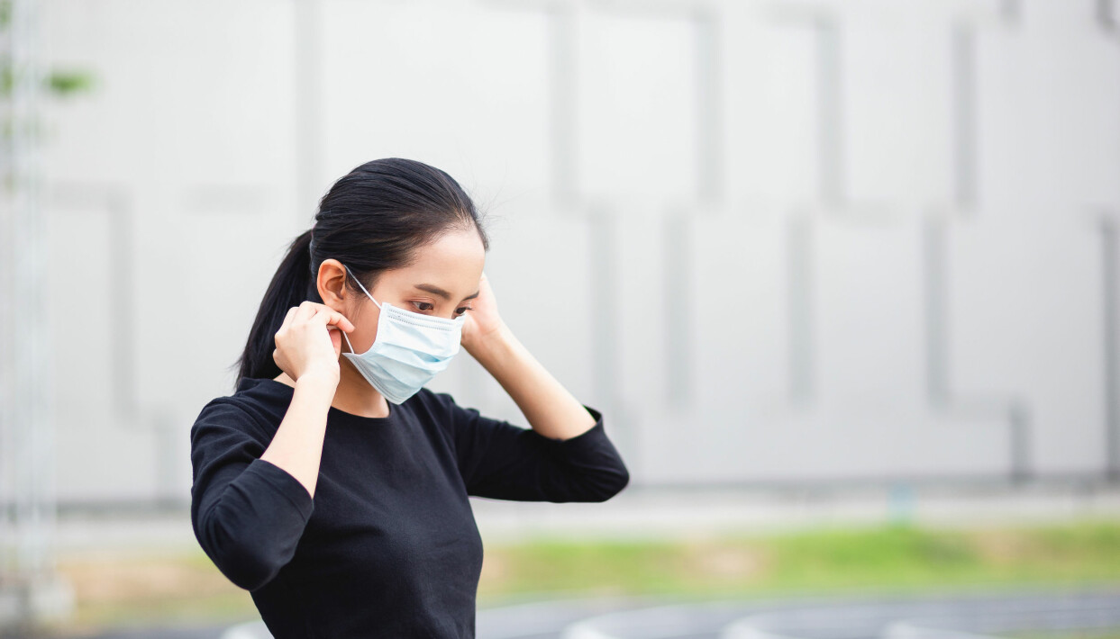 Att bära munskydd kan ge en falsk trygghet och ökar dessutom risken att vi rör oss i ansiktet, vilket kan bidra till smittspridningen. Foto: Shutterstock/TT Kvinna i svart tröja rättar till sitt munskydd.