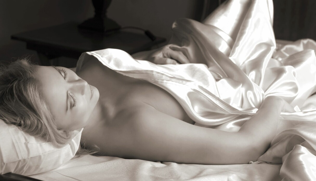Kvinna ligger avklädd i säng, ser ut att inte vilja ha sex