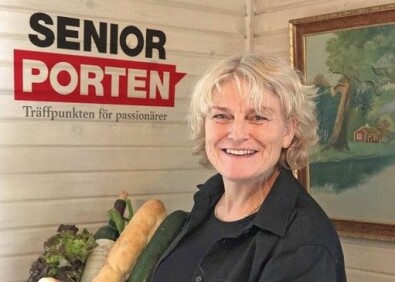 Marie Hedlund startade SeniorPorten för att kunna skapa ett ett mervärde i livet genom att ha möjlighet att träffa andra både digitalt och fysiskt. Kvinna med en korg med mat framför SeniorPortens logga.