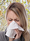 Kvinna med pollenallergi snyter sig.