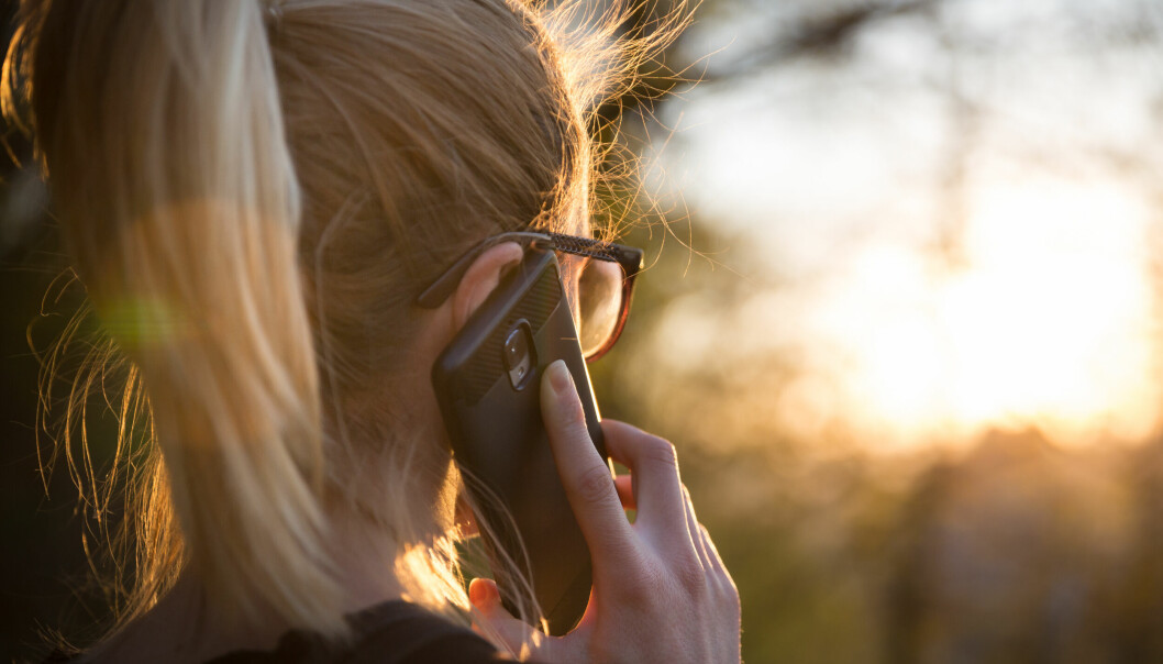 En kvinna pratar i telefon i solnedgång.