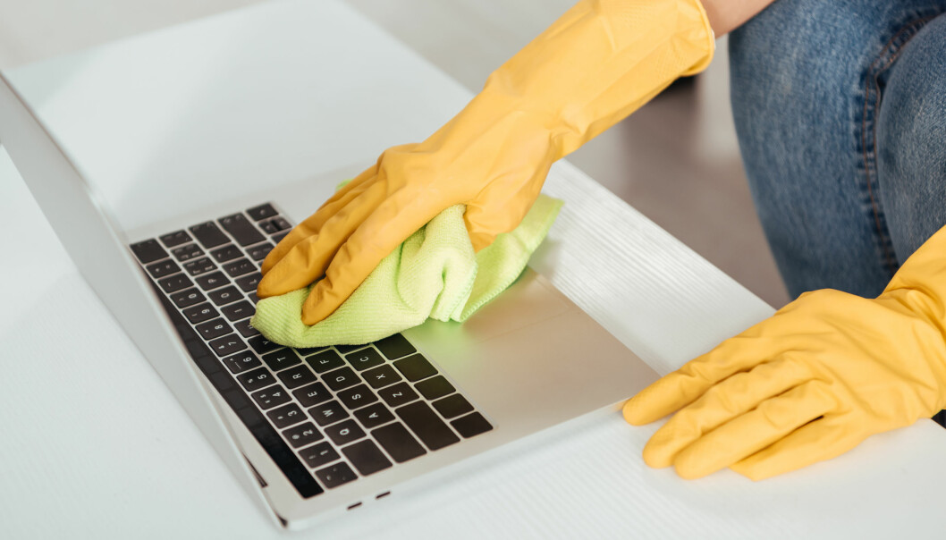 Kvinna rengör sitt tangentbord med en mikrofiberduk.