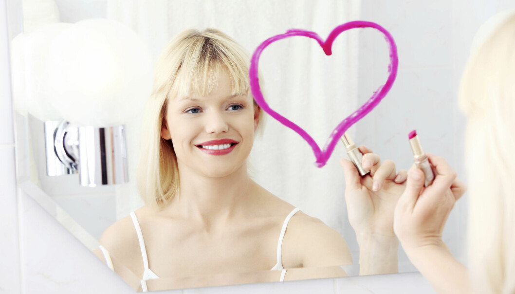 Kvinna ritar ett hjärta på en spegel för att bekräfta sig själv.