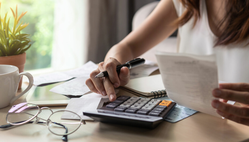 För vissa kvinnor kan ekonomin vara ett skäl till att stanna kvar i ett förhållande de inte är nöjda med. Foto: Shutterstock/TT Kvinna sitter vid ett bord med miniräknare och kvitton.